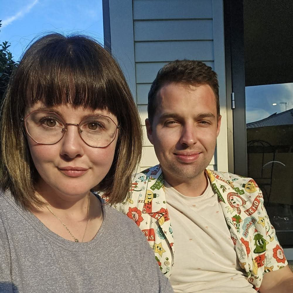 Maddi and Calum, the husband-and-wife team behind BabiFable, smiling together outside on a sunny evening