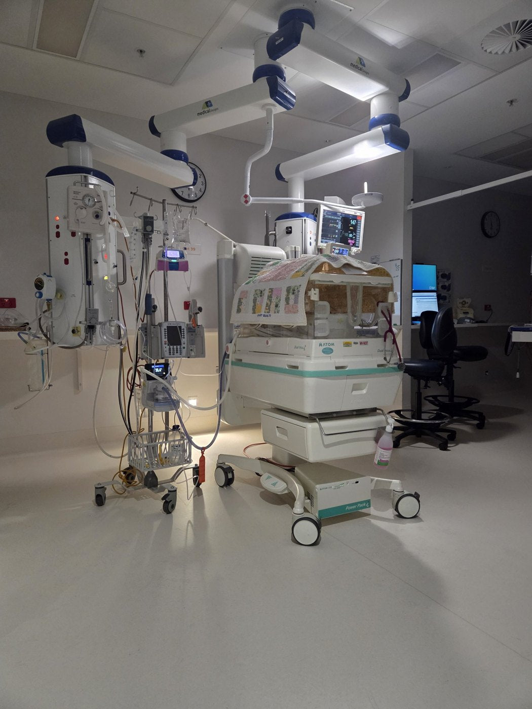 Our daughter's incubator in the NICU, surrounded by monitors, pumps and equipment under dim evening light